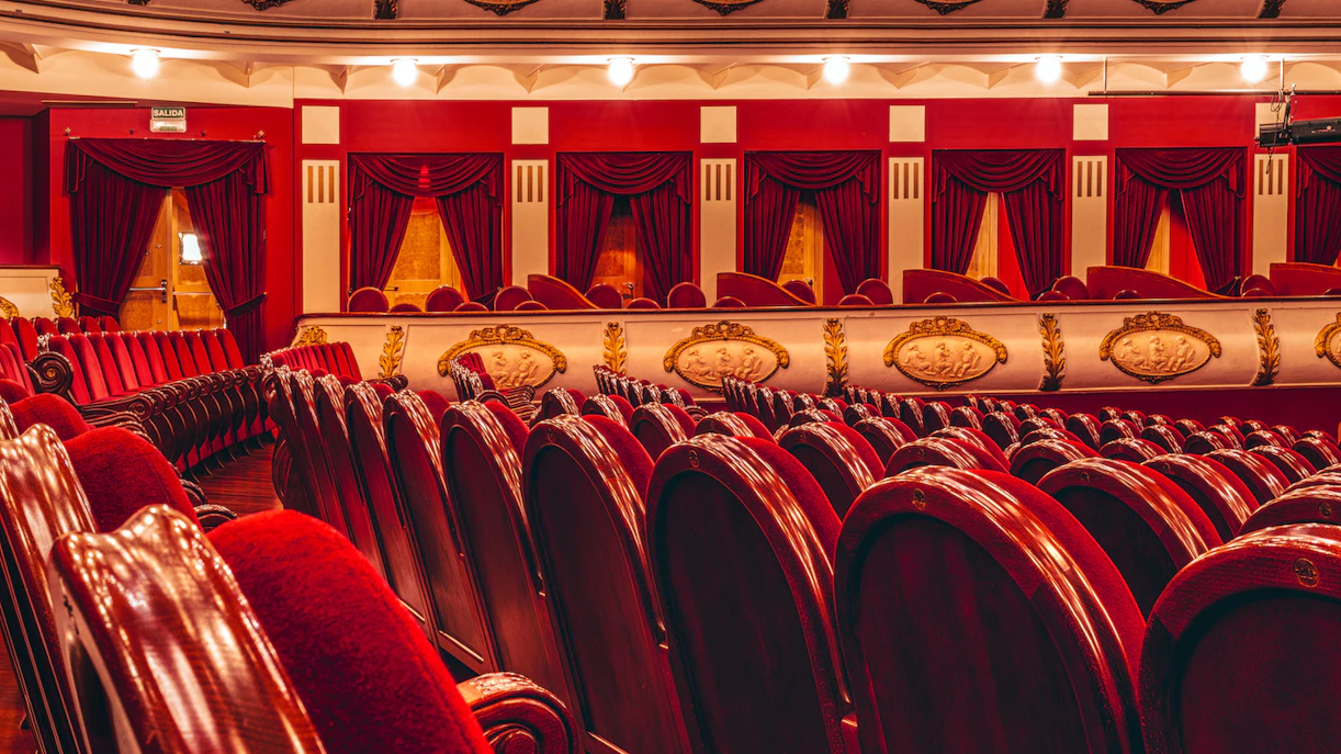 Adelphi Theatre stalls with ornate red seating and decorative balcony.