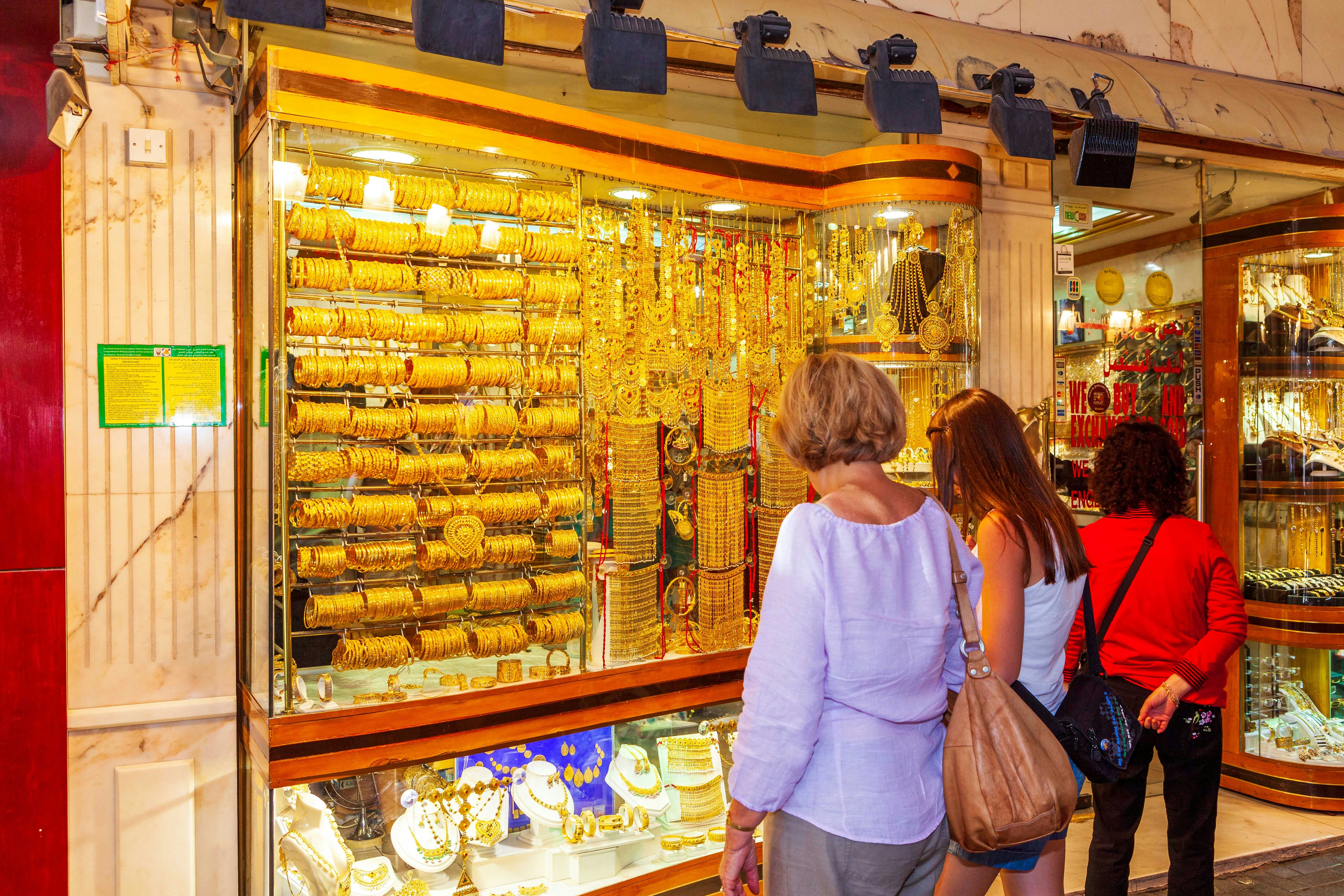 Shoppers admiring gold jewelry at Dubai Gold Souk during hop-on hop-off tour.