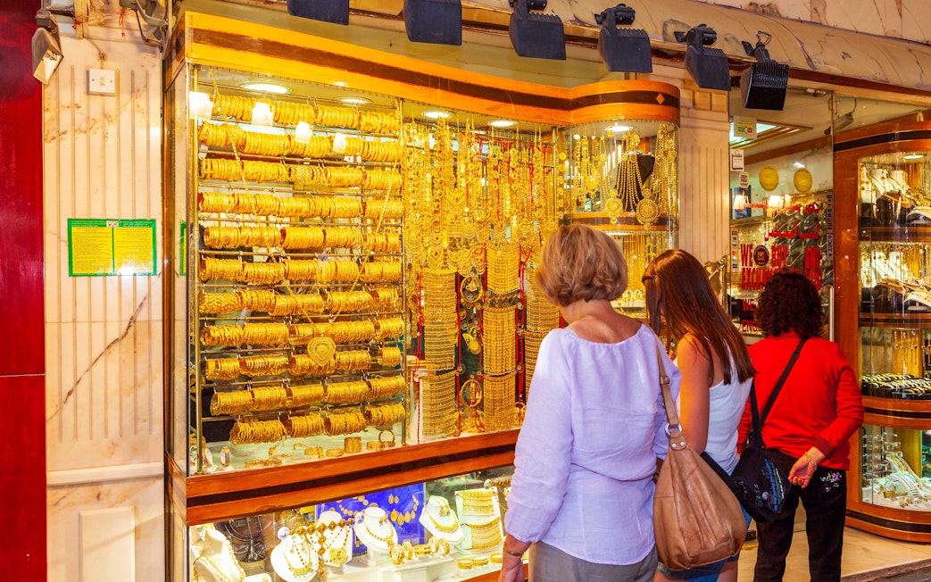 Shoppers admiring gold jewelry at Dubai Gold Souk during hop-on hop-off tour.