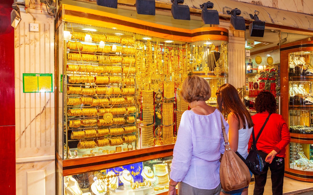 Shoppers admiring gold jewelry at Dubai Gold Souk during hop-on hop-off tour.