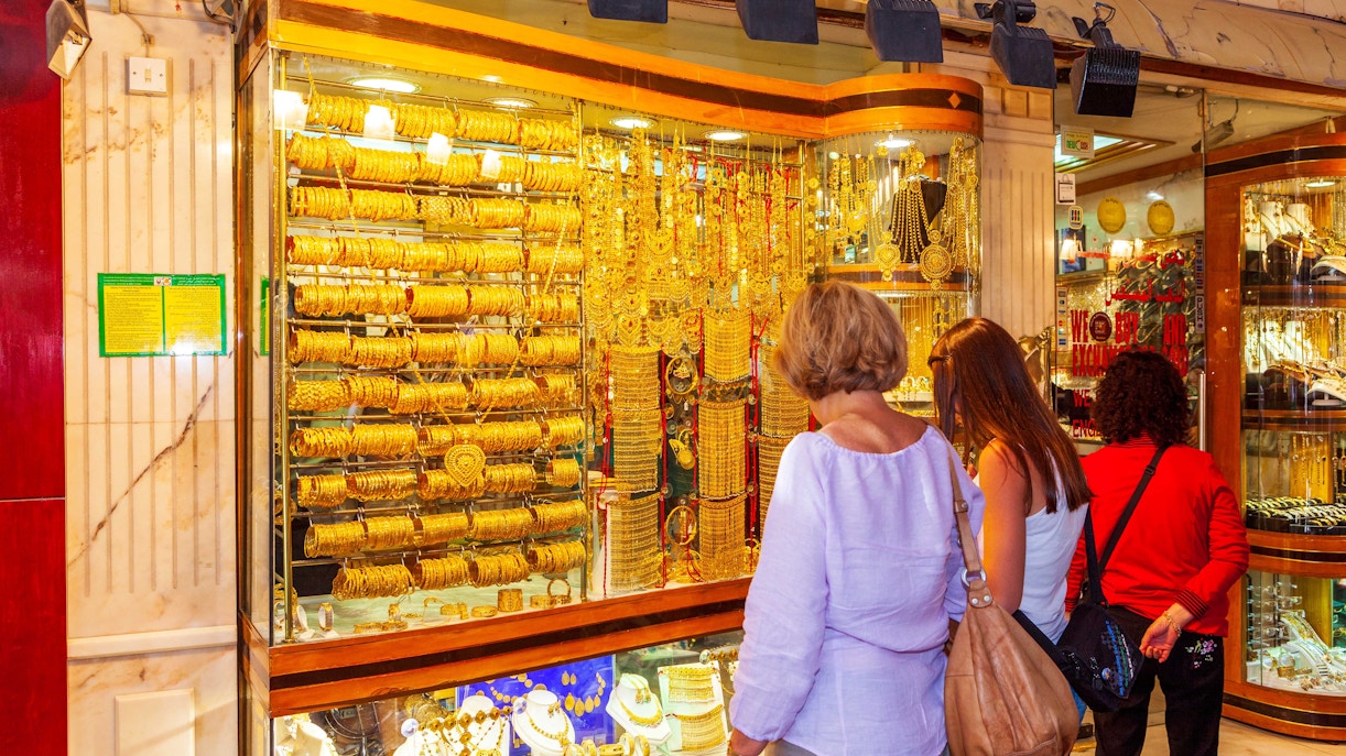 Shoppers admiring gold jewelry at Dubai Gold Souk during hop-on hop-off tour.
