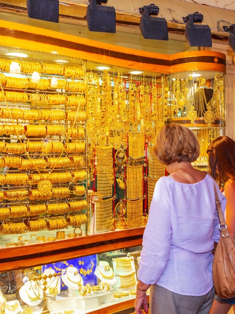 Shoppers admiring gold jewelry at Dubai Gold Souk during hop-on hop-off tour.