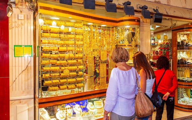 Shoppers admiring gold jewelry at Dubai Gold Souk during hop-on hop-off tour.