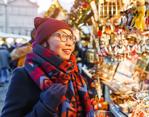 Shopper at Prague Christmas market browsing festive stalls.