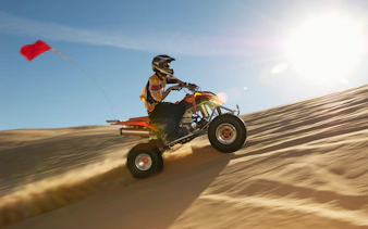 Quad biking on sand dunes in Dubai desert under bright sun.
