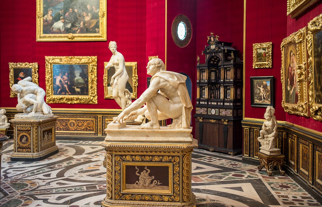 Interior of the Uffizi Gallery showcasing Renaissance sculptures and ornate paintings, highlighting the artistic legacy of Florence