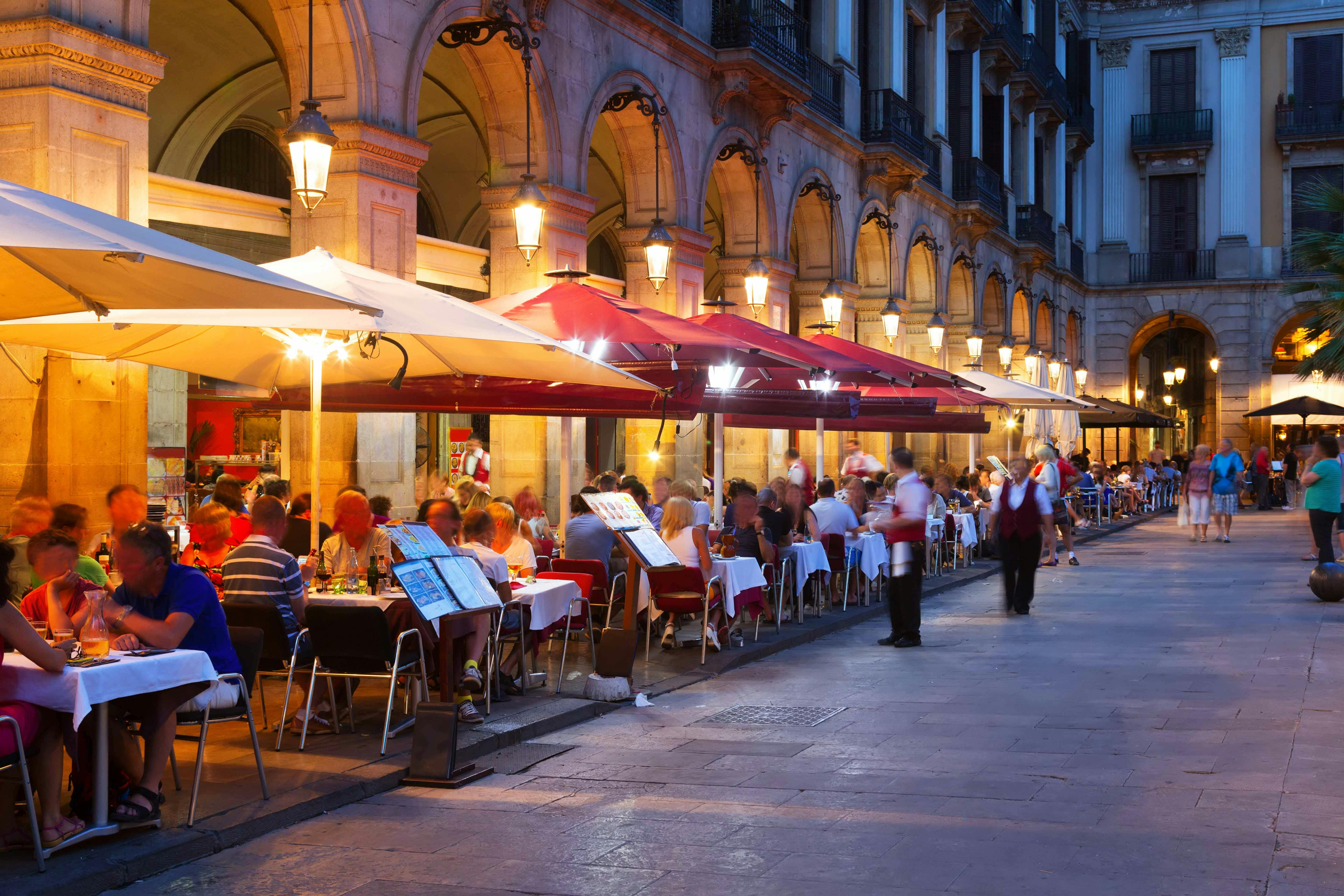 Outdoor dining at a bustling restaurant in Barcelona's historic district.