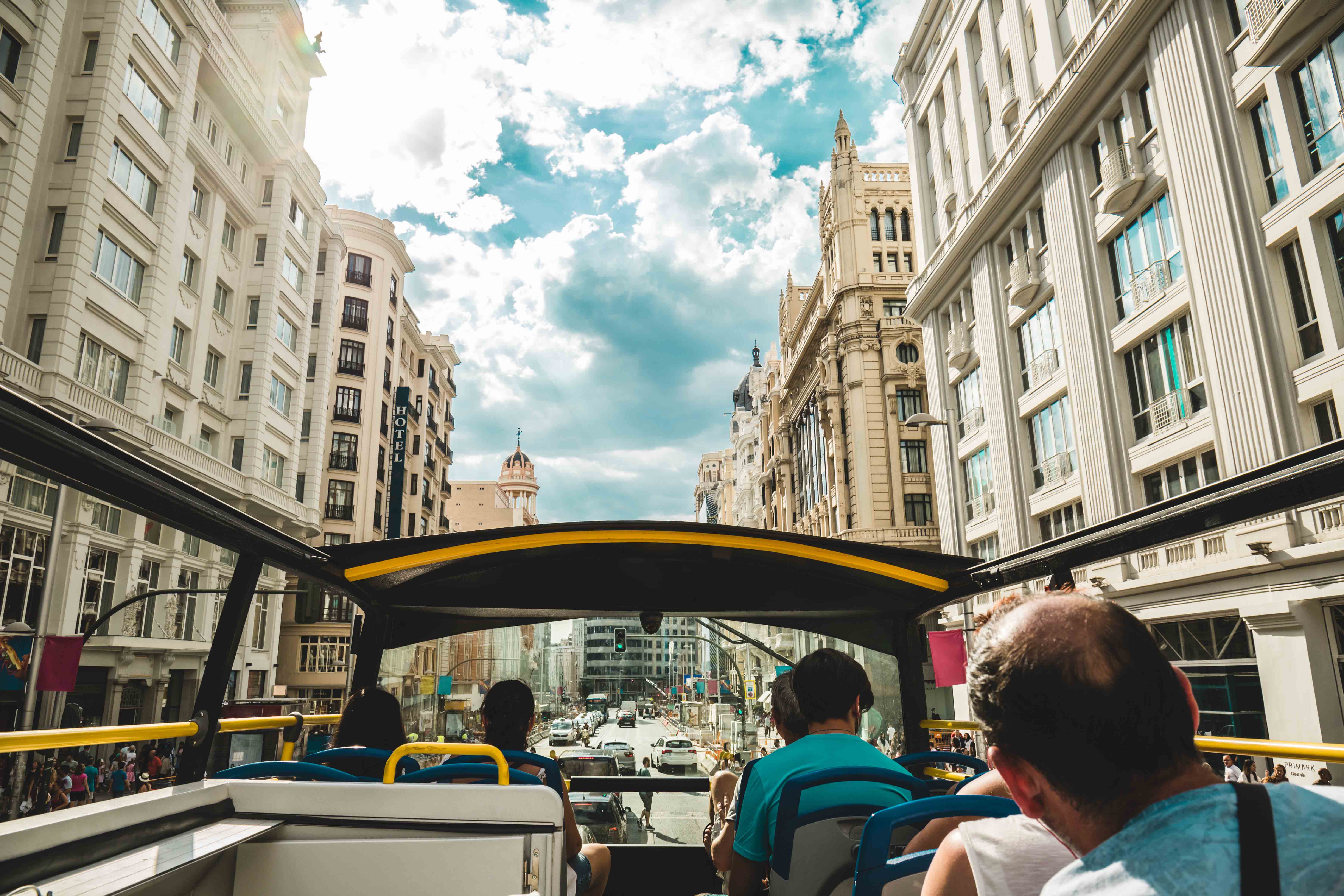 Open-top bus on Madrid City Tour passing Gran Vía buildings.