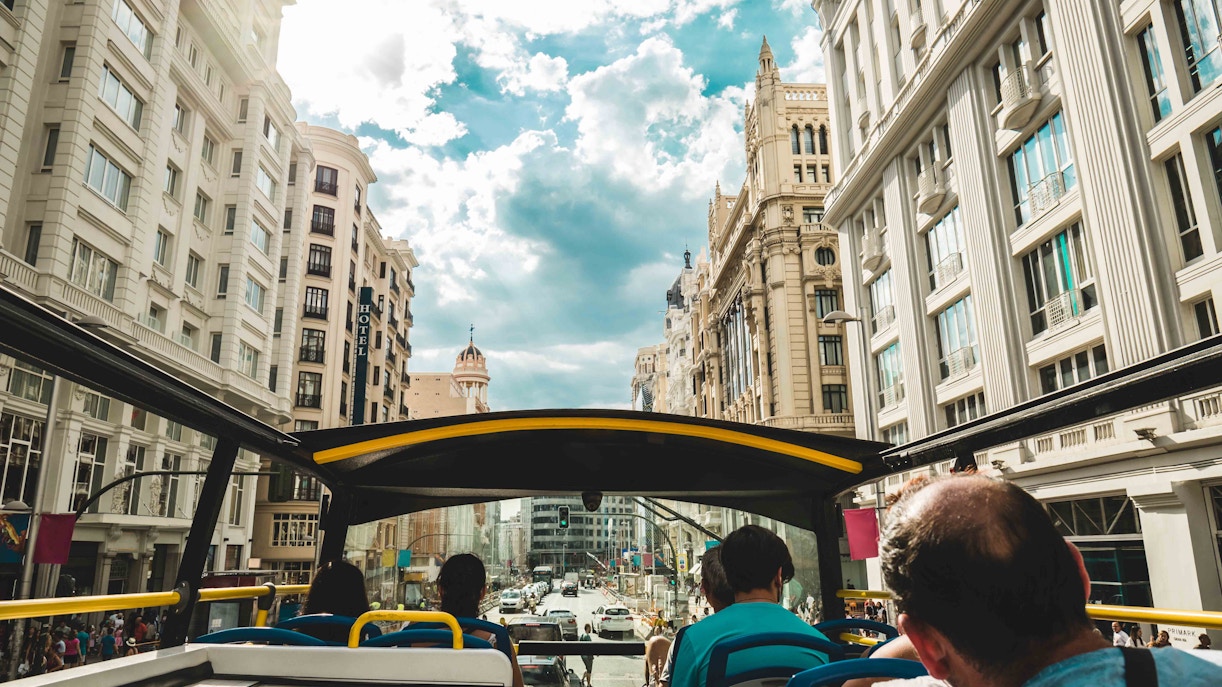 Open-top bus on Madrid City Tour passing Gran Vía buildings.