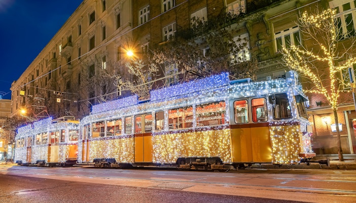 Tram adorned with festive lights on a Budapest street during Christmas.