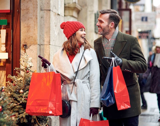 Couple shopping with bags on a festive street in Lisbon during Christmas.