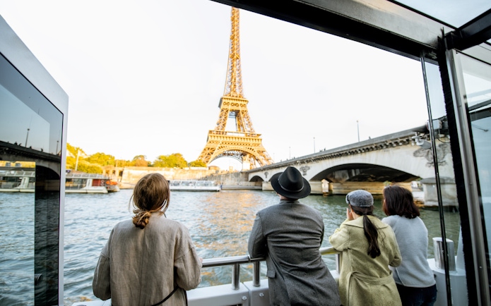 Family enjoying Seine River cruise with view of Eiffel Tower in Paris.
