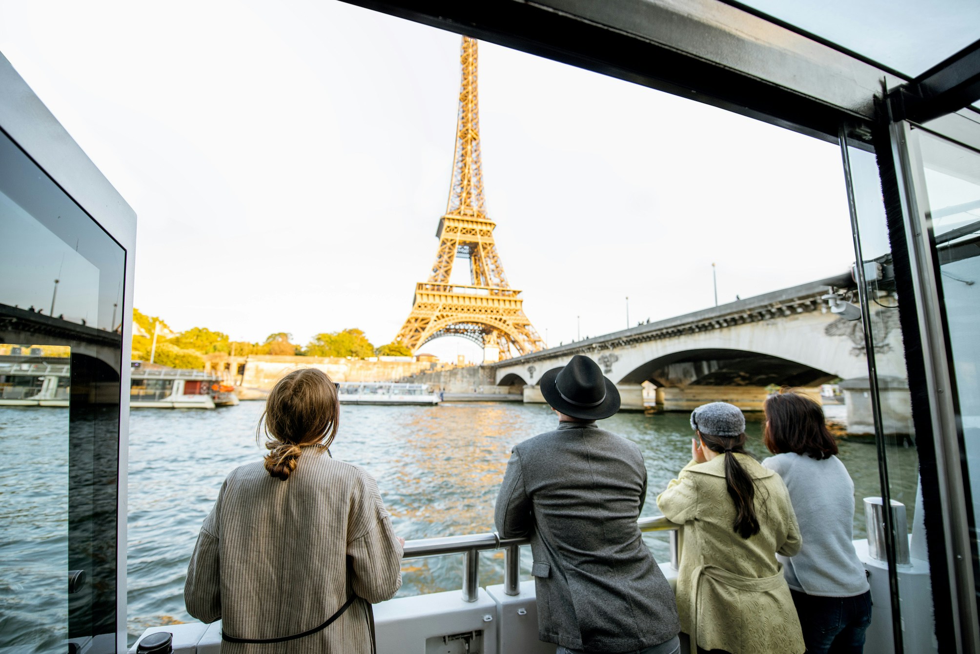 Family enjoying a Seine River cruise in Paris with iconic Eiffel Tower in the background.