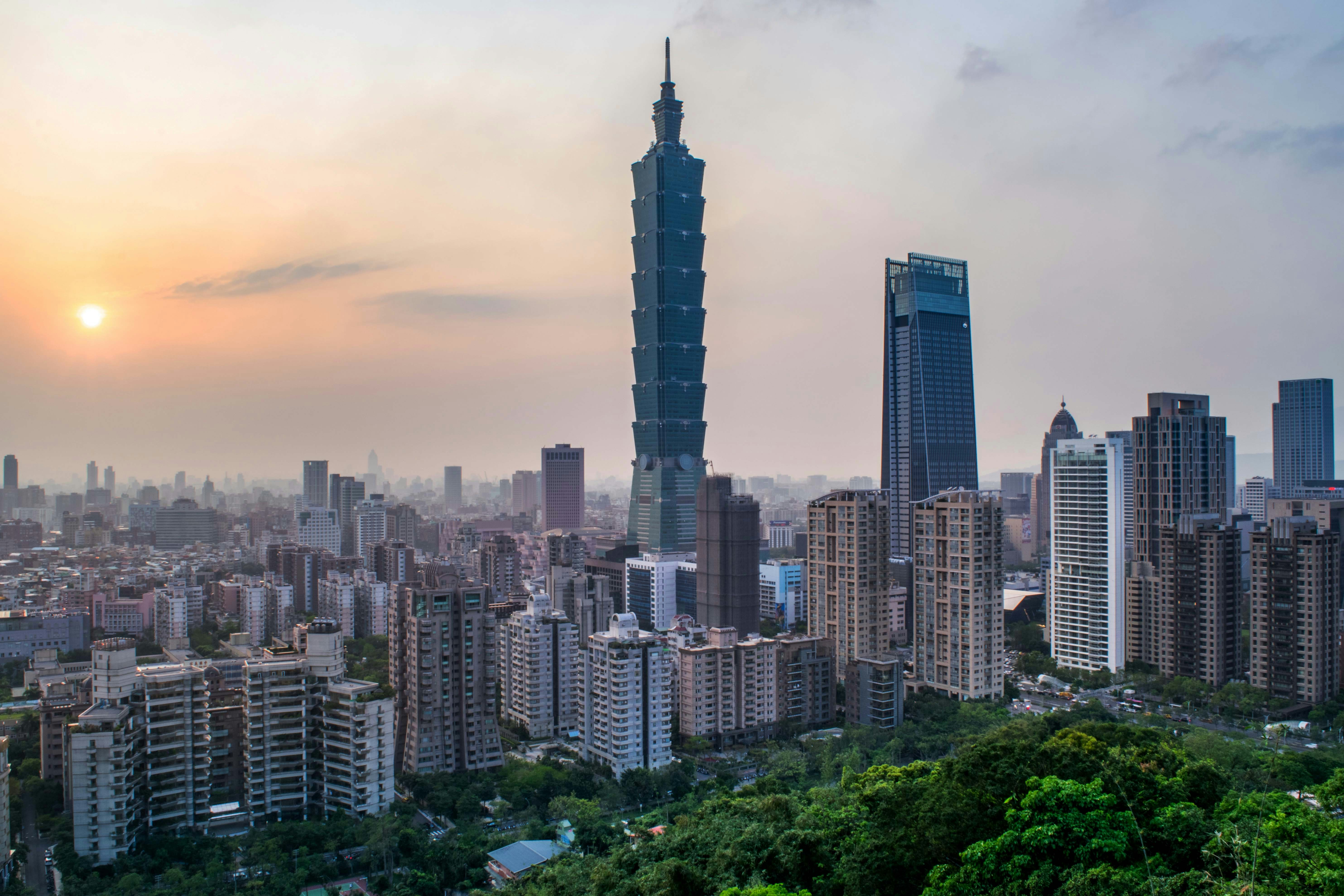 Taipei 101 towering over Taipei cityscape at sunset.
