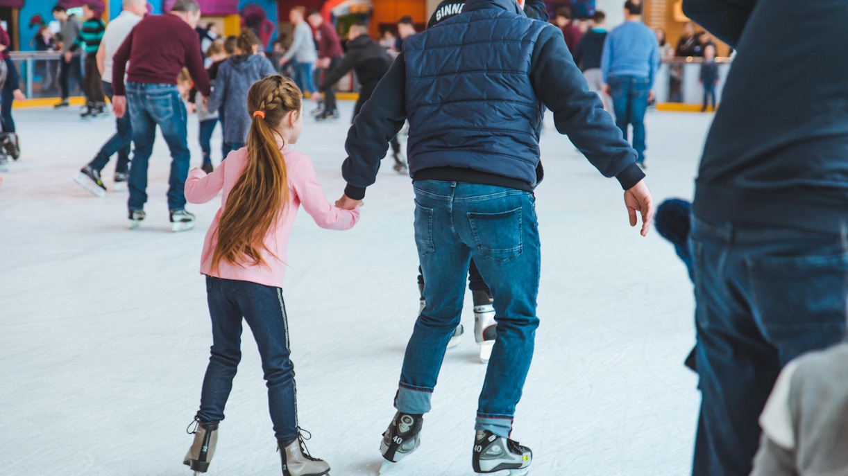 People ice skating at Snow City, Singapore, with colorful murals in the background.