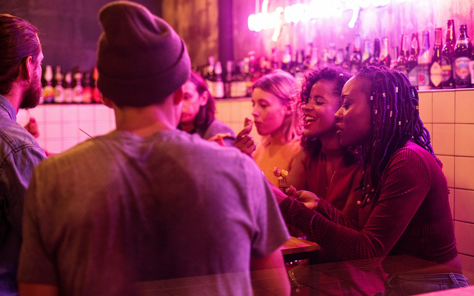 Group enjoying New Year's Eve party in Amsterdam bar with neon lights.