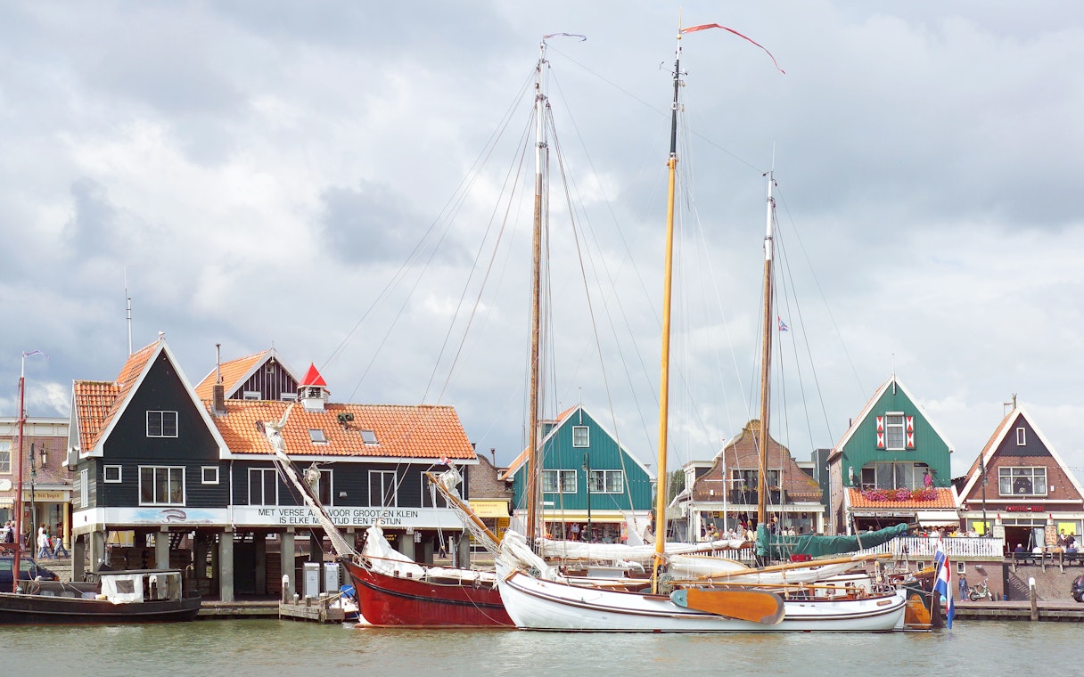 Sailboats docked in front of traditional Dutch houses in Volendam, Netherlands.