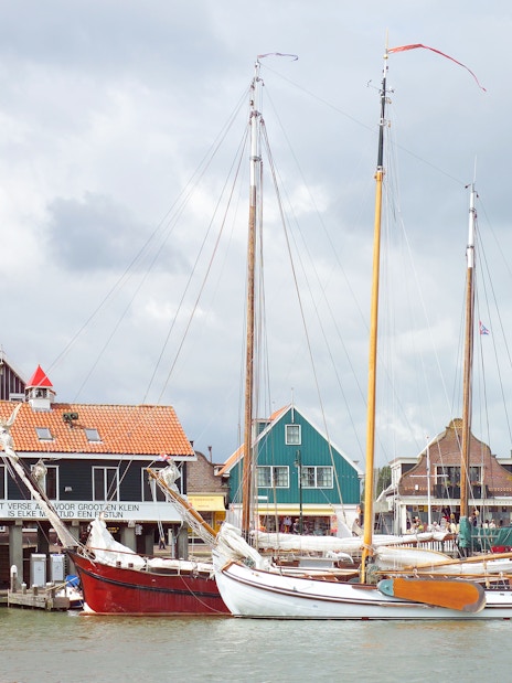 Sailboats docked in front of traditional Dutch houses in Volendam, Netherlands.