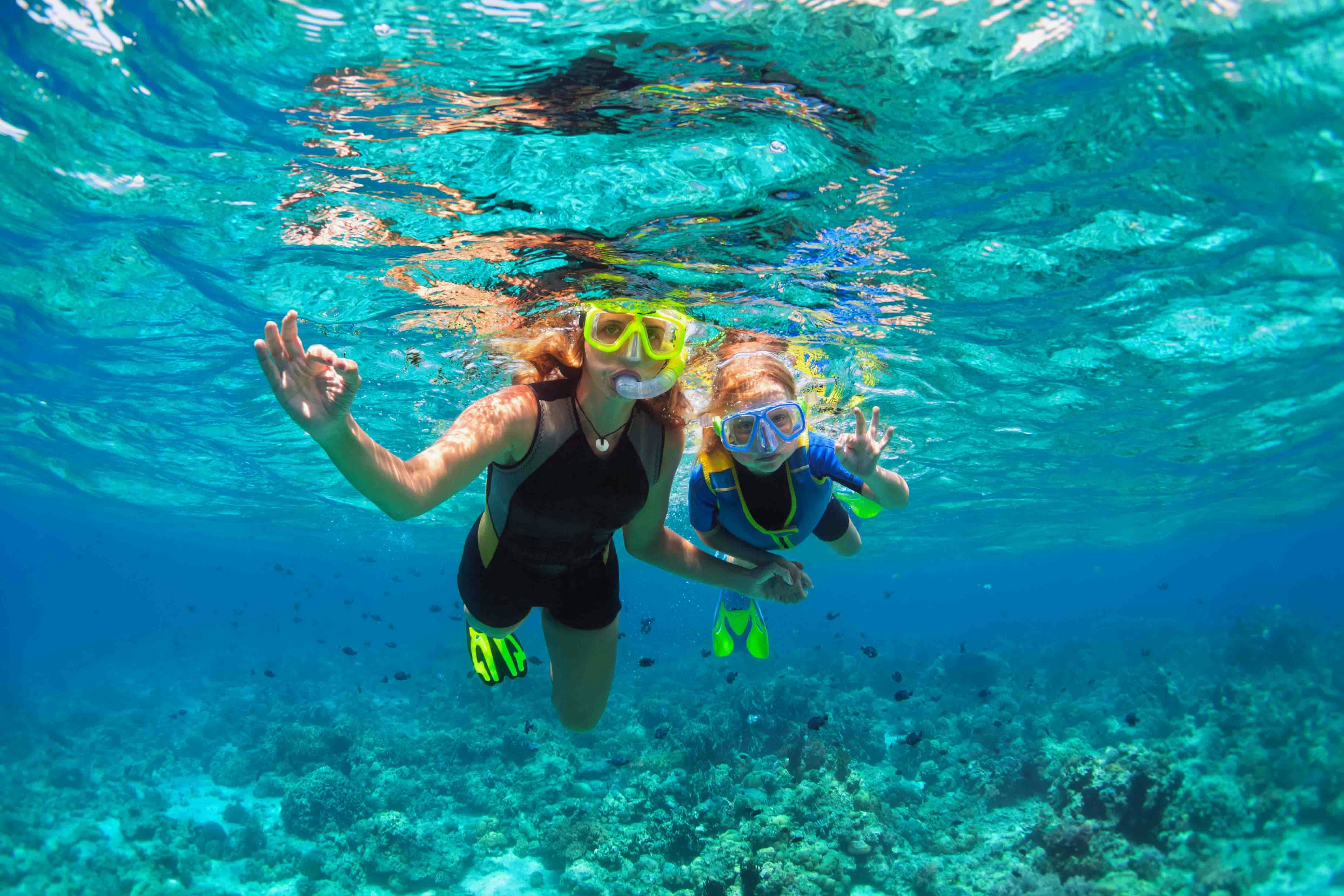 Tourists snorkeling in clear waters of Nusa Penida, Indonesia, exploring vibrant marine life.