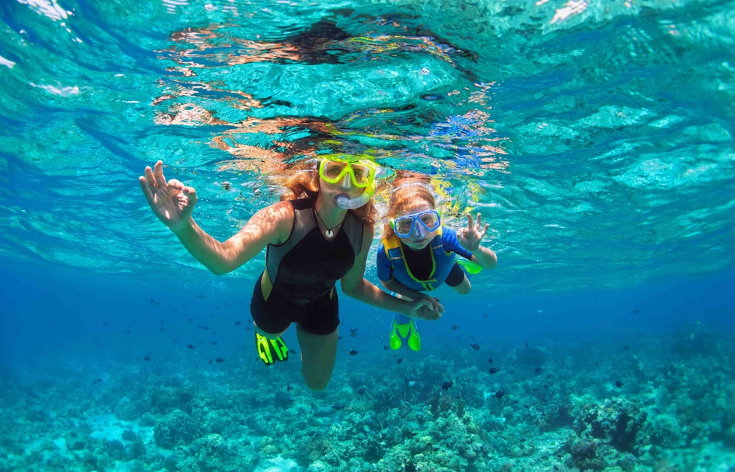 Tourists snorkeling in clear waters over coral reefs at Nusa Penida, Indonesia.