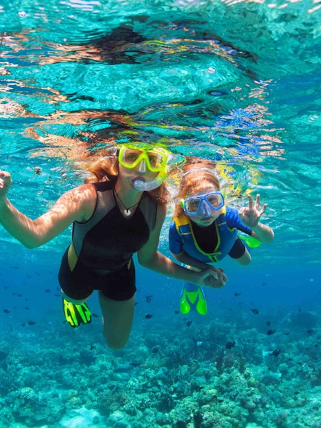 Tourists snorkeling in clear waters over coral reefs at Nusa Penida, Indonesia.