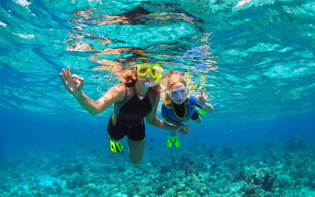 Tourists snorkeling in clear waters over coral reefs at Nusa Penida, Indonesia.