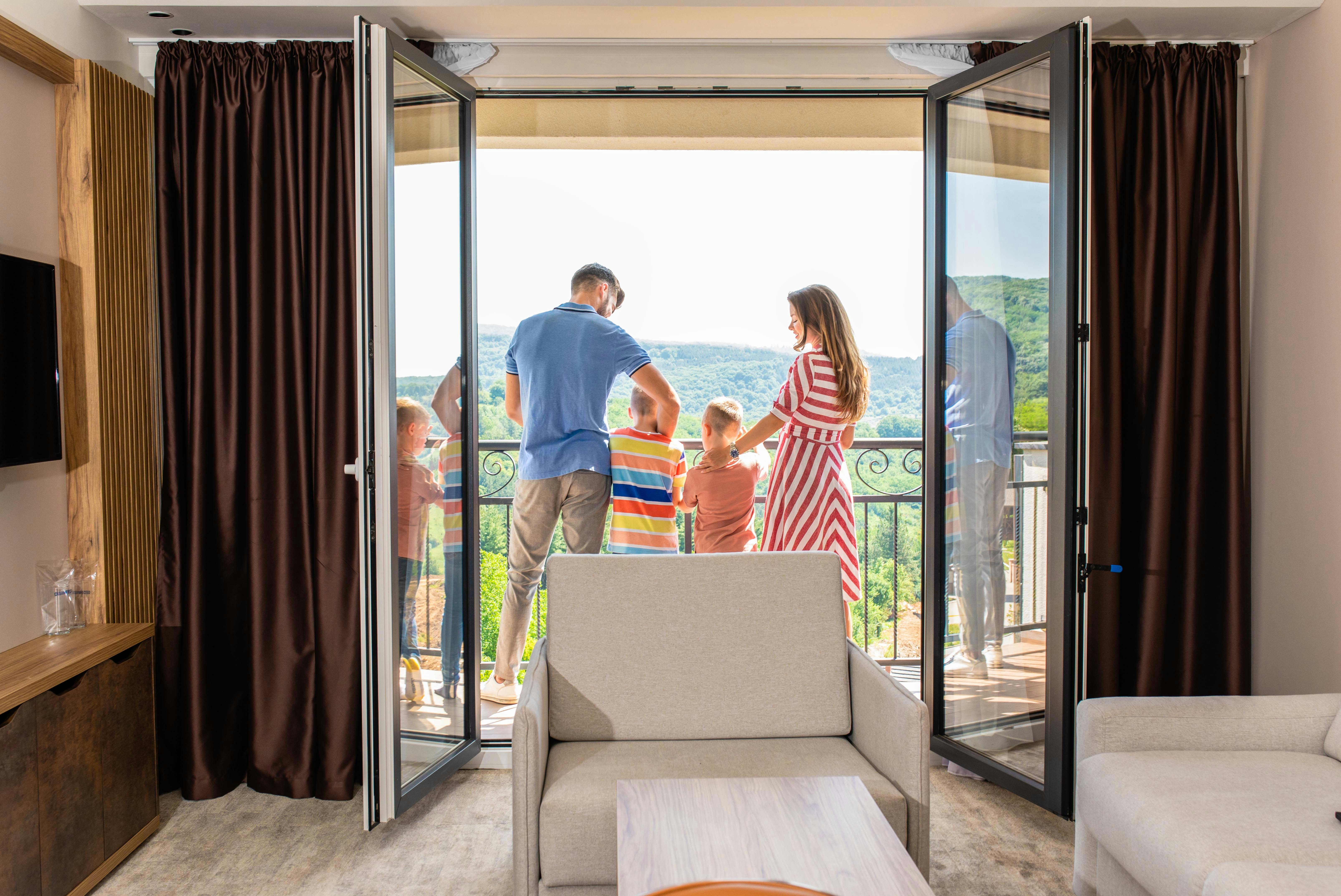 Family enjoying balcony view hotel room.