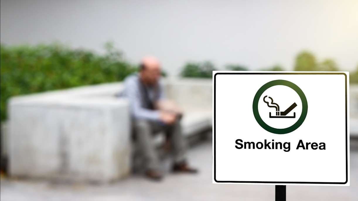 Smoking area sign with seating in the background.