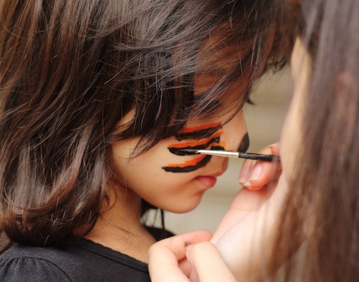 Child receiving face painting at Sigurta Park event.
