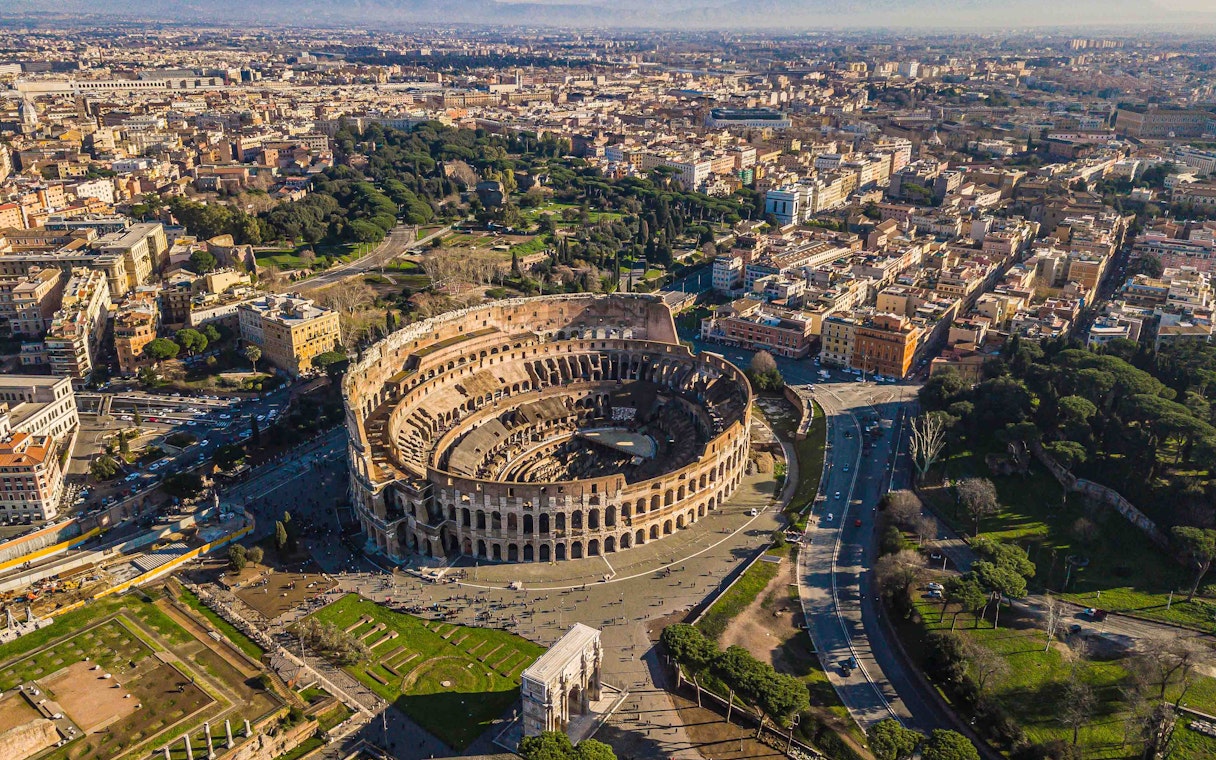 Aerial view of the Colosseum in Rome, Italy, surrounded by cityscape and roads.