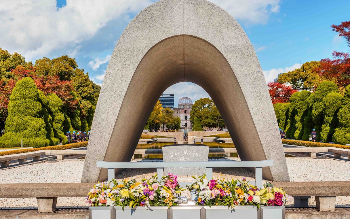 Hiroshima Peace Memorial Park cenotaph with Atomic Bomb Dome in background.