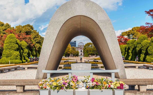 Hiroshima Peace Memorial Park cenotaph with Atomic Bomb Dome in background.