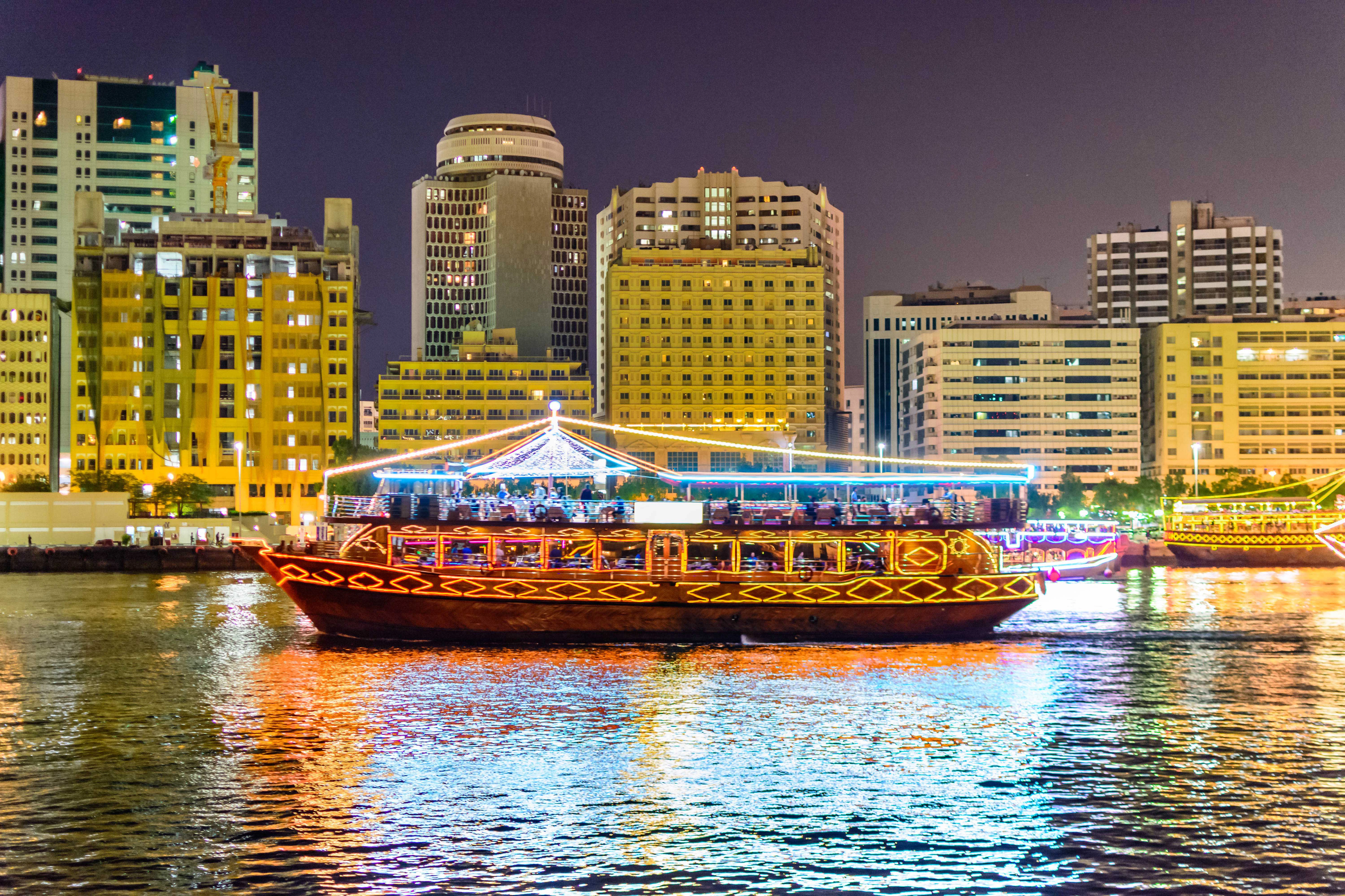 Dhow cruise on Dubai Creek with city skyline at night.