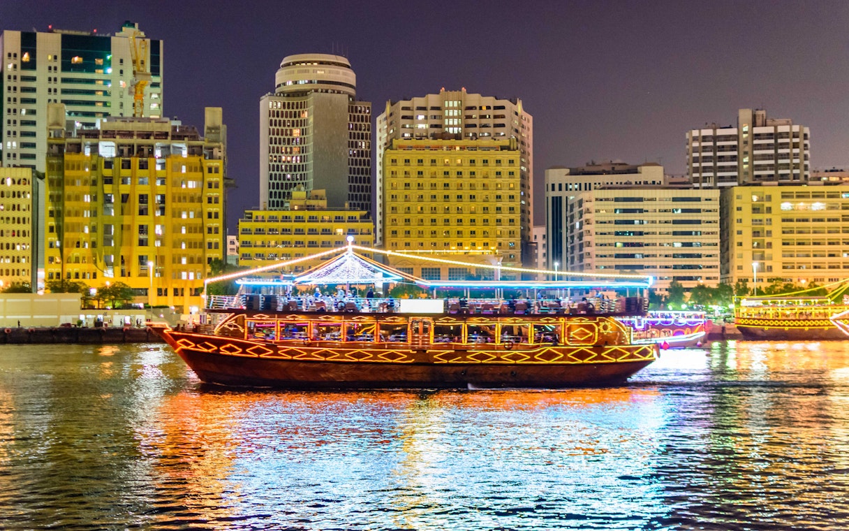Dhow cruise on Dubai Creek with city skyline at night.