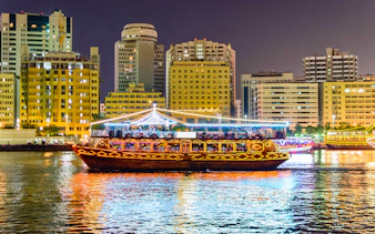 Dhow cruise on Dubai Creek with city skyline at night.