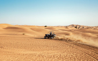 Dune buggy driving through desert sands in Dubai.