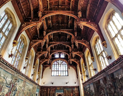 Tourists exploring the historic Great Hall at Hampton Court, showcasing its grand architecture and unique artifacts