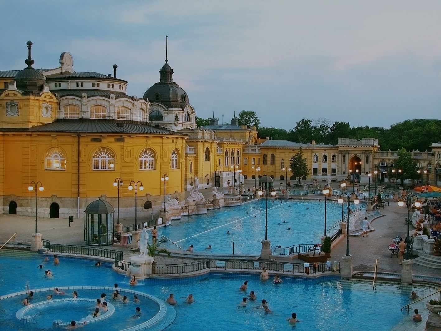 People enjoying thermal baths in Budapest with historic architecture in the background.