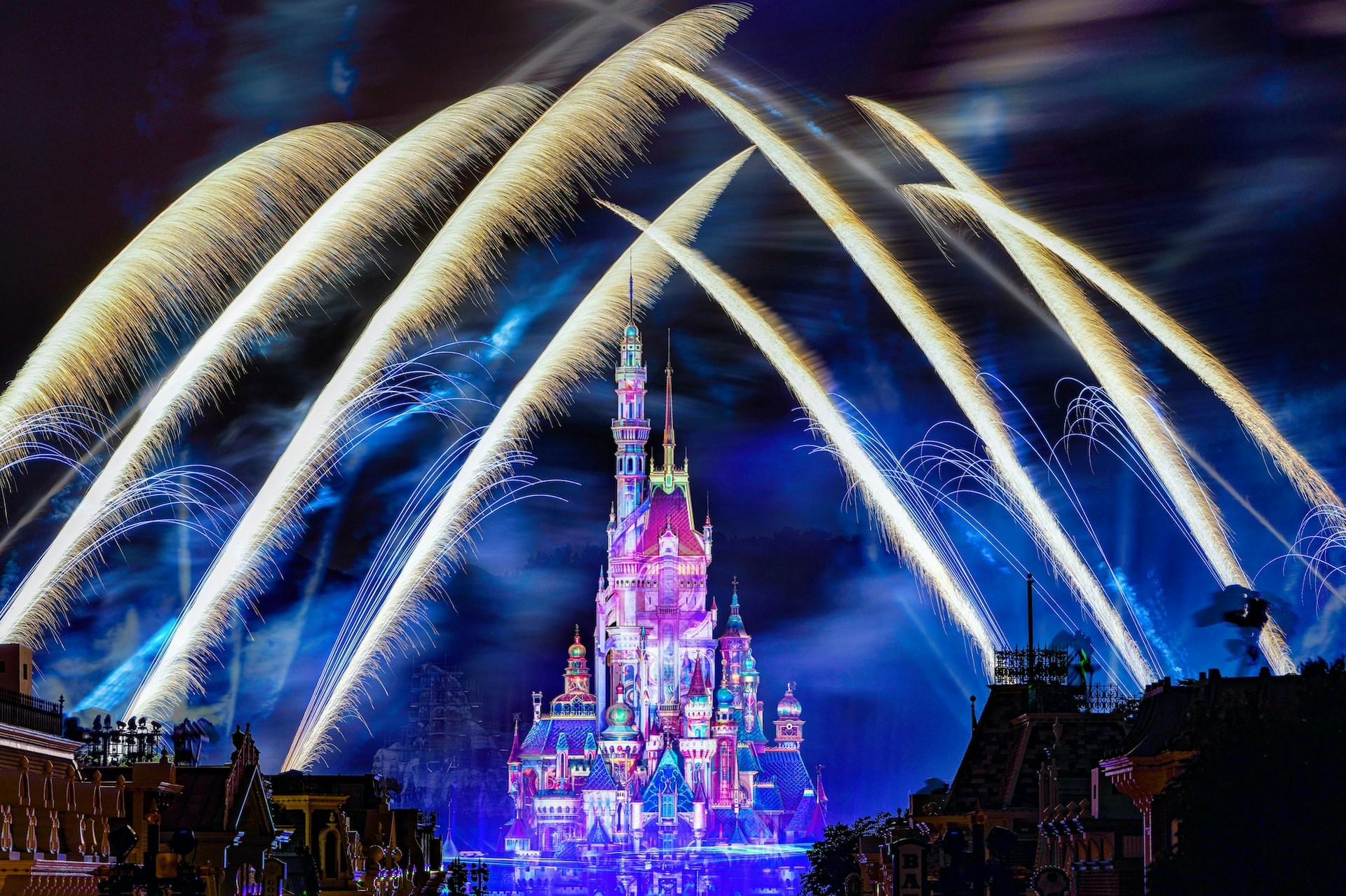 Fireworks over illuminated castle during Disney Illuminations show at night.