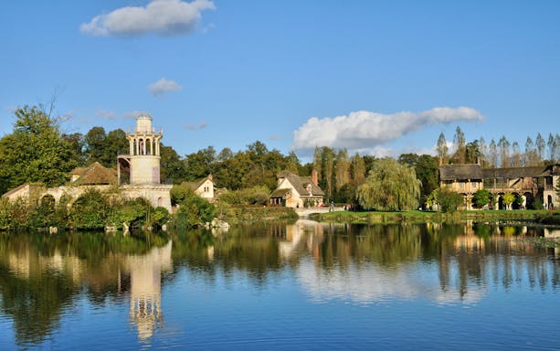 Grand Trianon at Versailles with gardens and lake reflection.