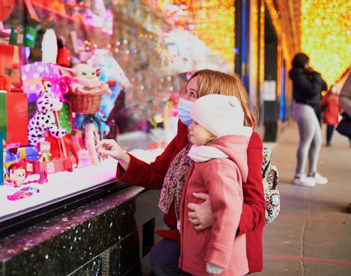 Mother and child admire festive window display at Paris department store during Christmas.
