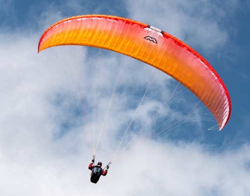 Paraglider soaring in the sky during Interlaken paragliding experience.