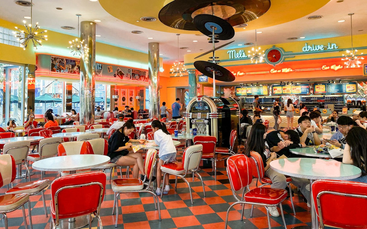 Retro diner with red chairs and neon lights at Sentosa, Singapore, guests dining and enjoying meals.