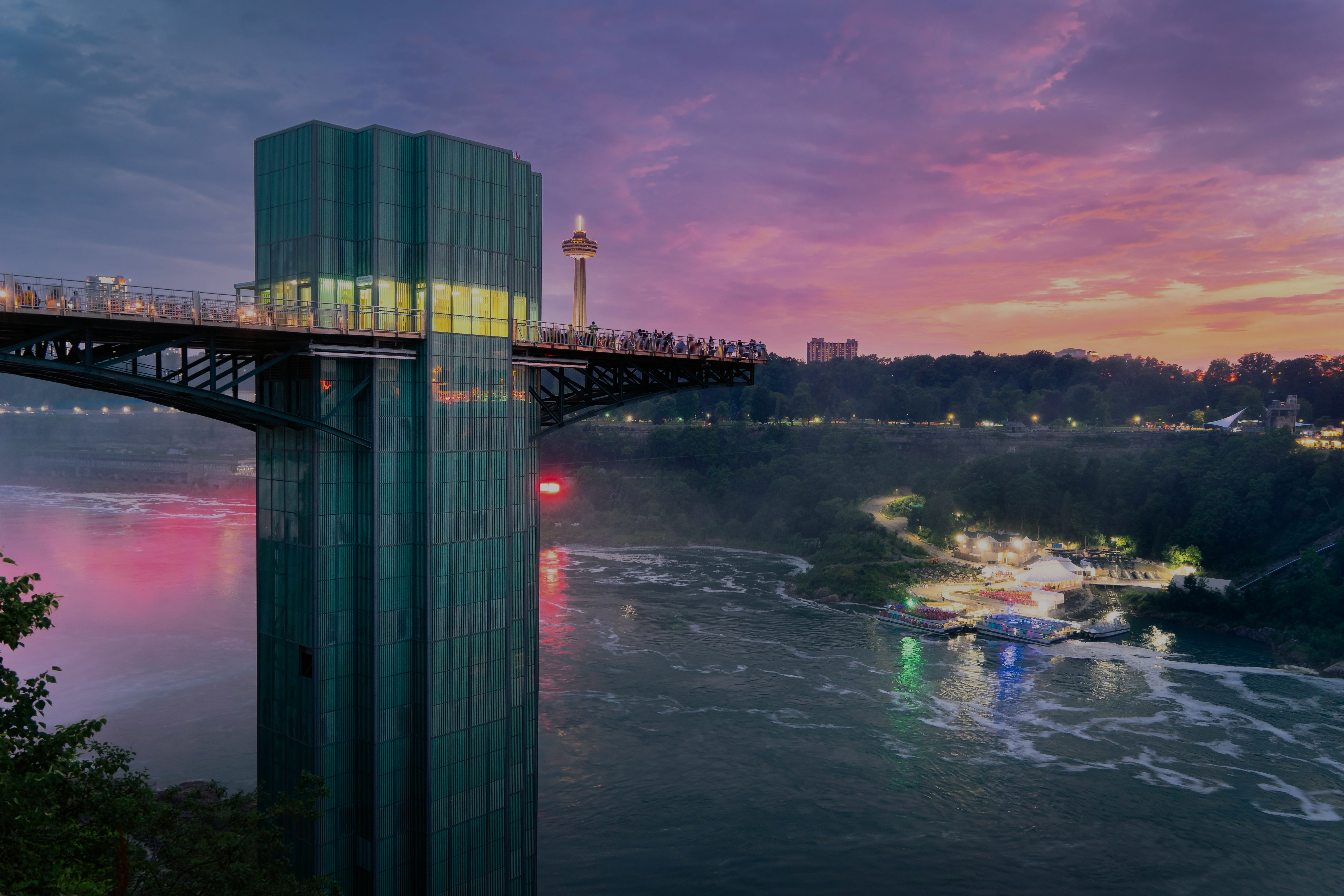 Observation deck overlooking Niagara Falls at sunset, with cityscape and river views.
