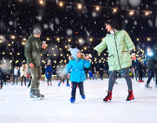 Ice skating in Paris at night with festive lights and snowfall.