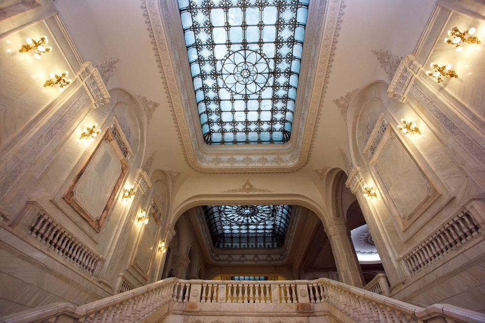 Stained glass ceiling and ornate staircase inside the Palace of Parliament, Bucharest.