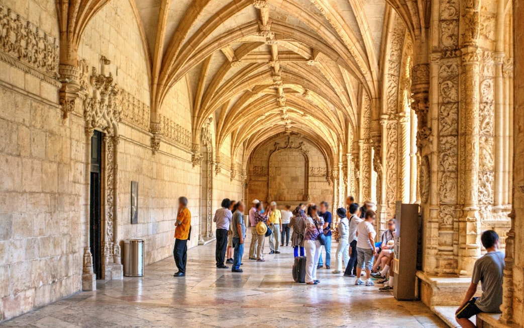 Visitors exploring the ornate cloisters of Jeronimos Monastery in Lisbon, Portugal.