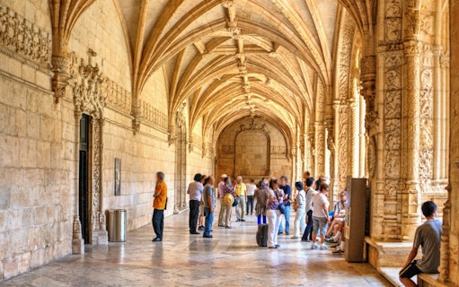 Visitors exploring the ornate cloisters of Jeronimos Monastery in Lisbon, Portugal.