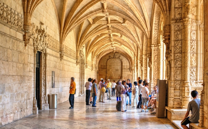 Visitors exploring the ornate cloisters of Jeronimos Monastery in Lisbon, Portugal.