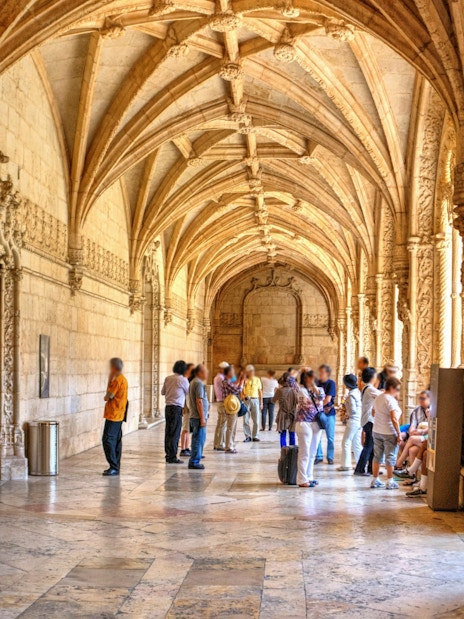 Visitors exploring the ornate cloisters of Jeronimos Monastery in Lisbon, Portugal.